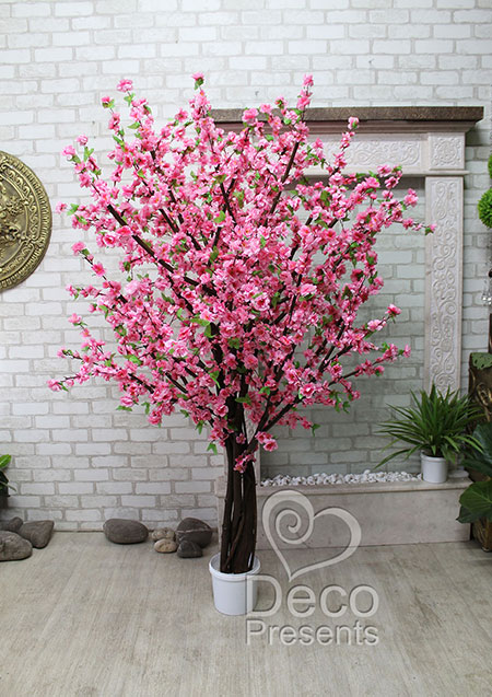 Large decorative wedding tree made from natural wooden branches and artificial pink sakura flowers